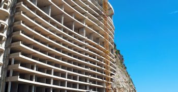 House construction in Petrovac, Montenegro House construction with crane and parked cars in Petrovac, Montenegro